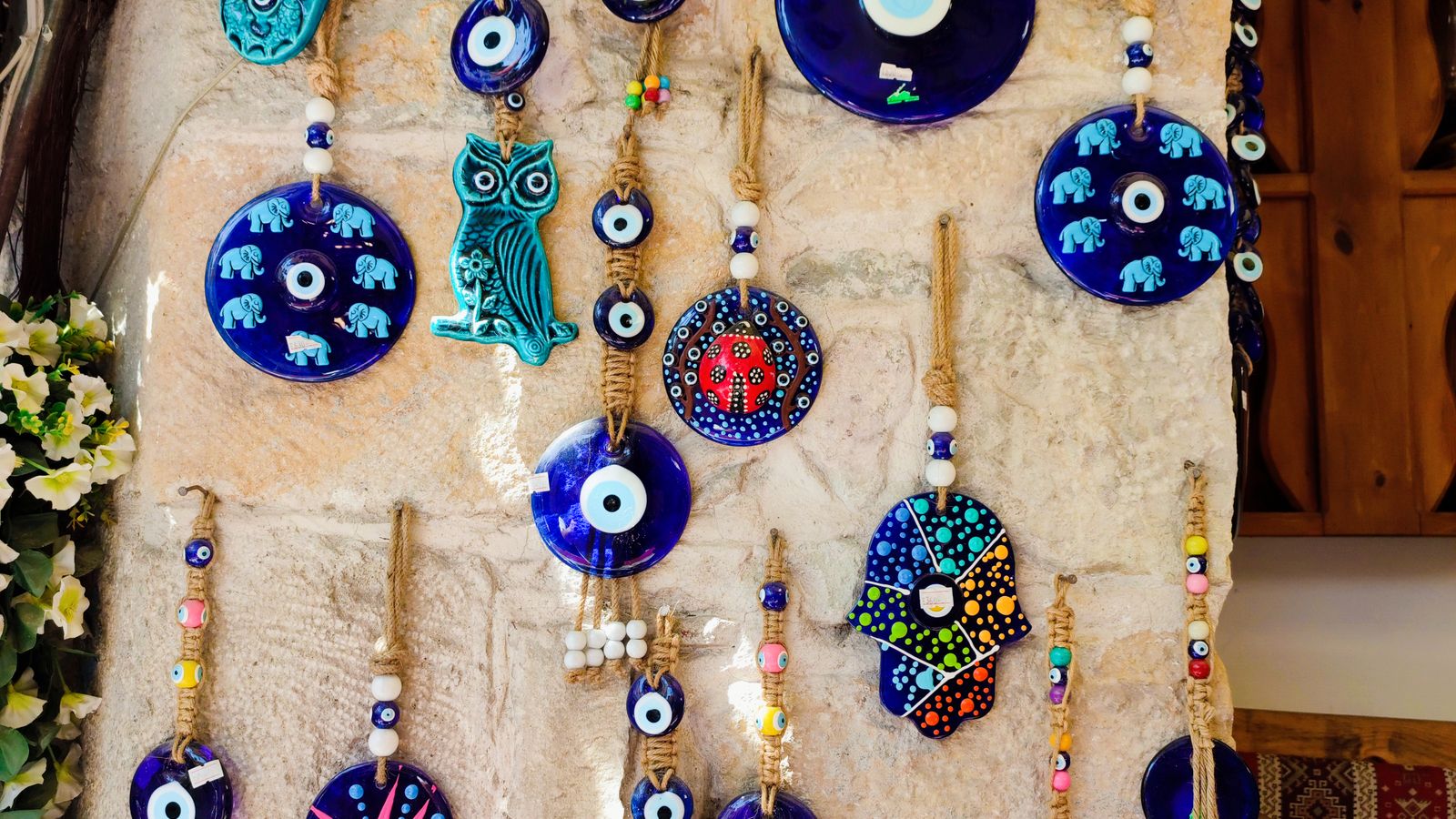 Amulettes contre le mauvais oeil accrochees a un mur, nazar bleus et main de Fatma