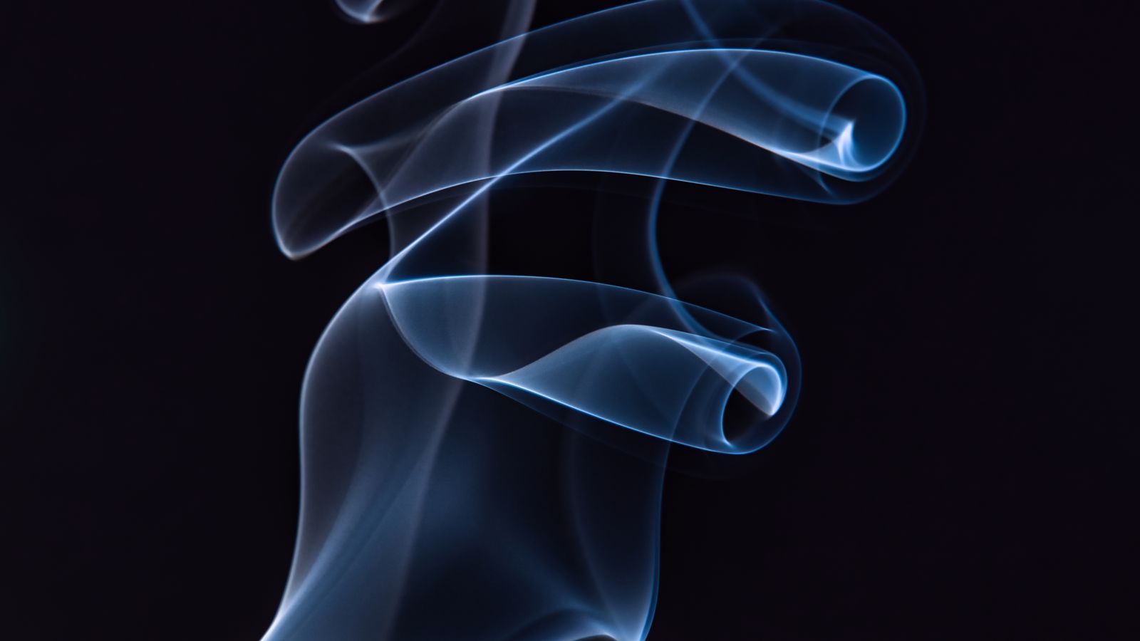 Volute de fumée bleutée sur fond noir, rituel de désenvoûtement à distance