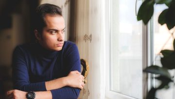 Homme pensif regardant par la fenetre, se demandant s'il est envoute