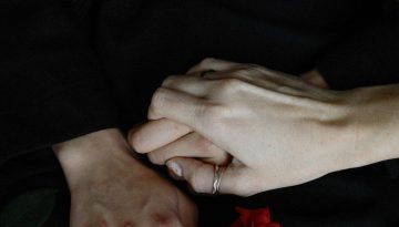 Mains enlacees pres d'une rose rouge, emprise d'un envoutement amoureux