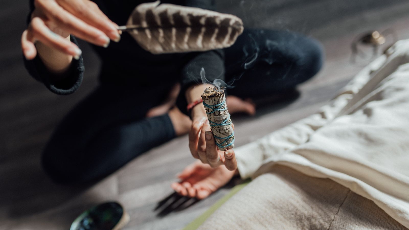 Mains tenant un bâton de sauge qui fume, nettoyer son énergie après un contact difficile